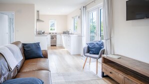 Un salon moderne avec un canapé en cuir, un buffet en bois et un fauteuil gris.