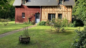 A two-story house with a red and beige exterior, a sloped roof, and a small front porch. - Maison de Campagne Rivière et Forêt (Le Brévedent)