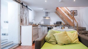 Une cuisine compacte dotée d’un four encastré, un coin repas avec une table et des chaises, et un escalier menant à un niveau supérieur.