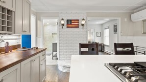 A modern kitchen with white cabinetry, a wooden countertop, and a central island with a stove. - Dog-Friendly West End Home + Parking - Sleeps 6 (Provincetown)