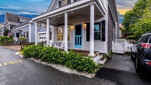 A two-story house with a porch, a blue door, and a white fence. - Dog-Friendly West End Home + Parking - Sleeps 6 (Provincetown)