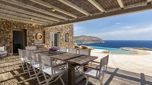Una terraza de madera con un muro de piedra y vista al océano.