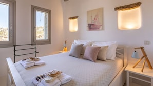 Un dormitorio ordenado con cama, almohadas y mesita de noche con lámpara.