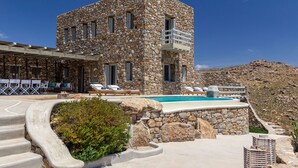 Un edificio de piedra con piscina, mobiliario exterior y vistas del paisaje circundante.