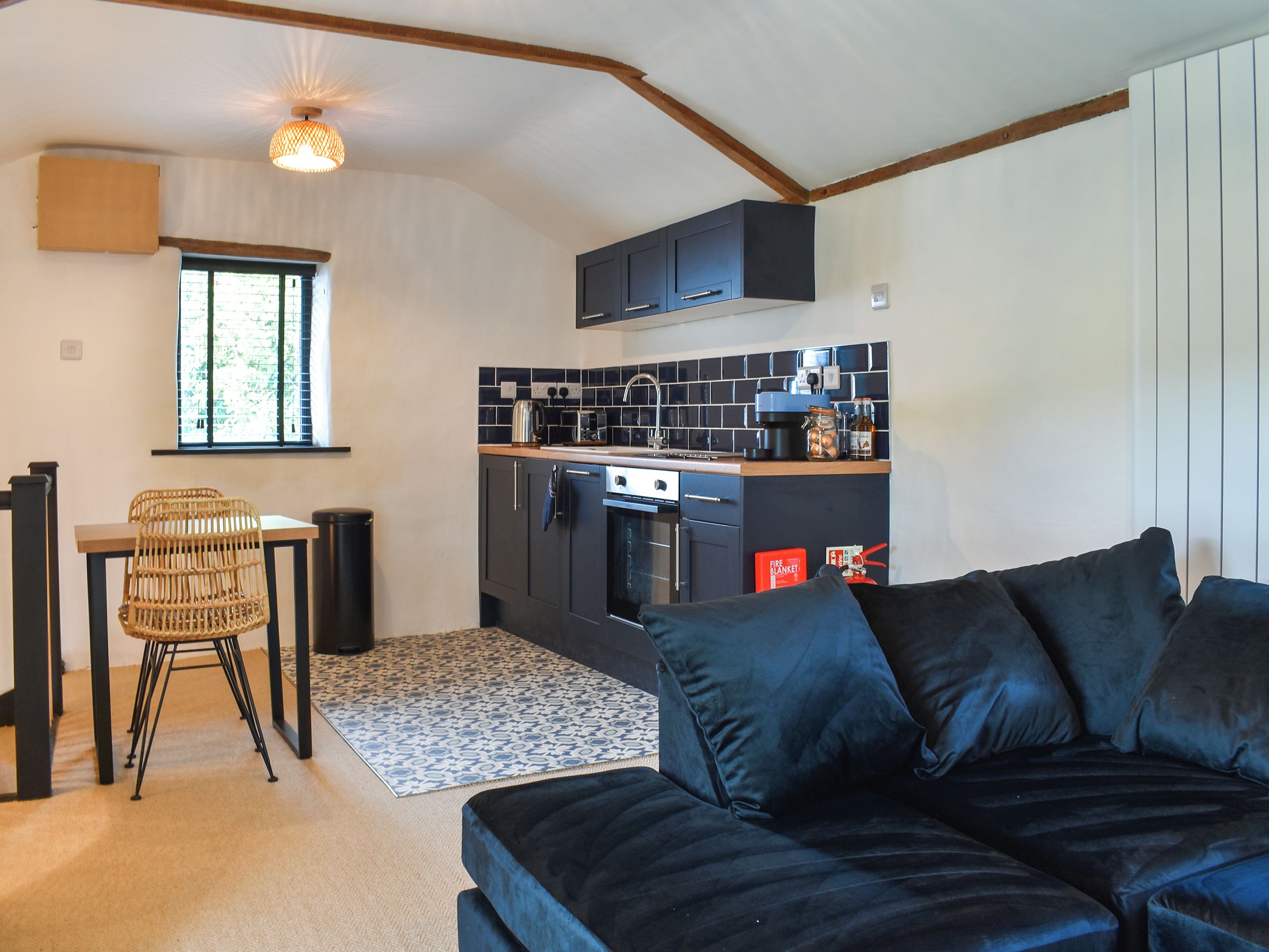 A compact living space with a kitchenette, a sofa, a dining table with chairs, and a patterned rug.