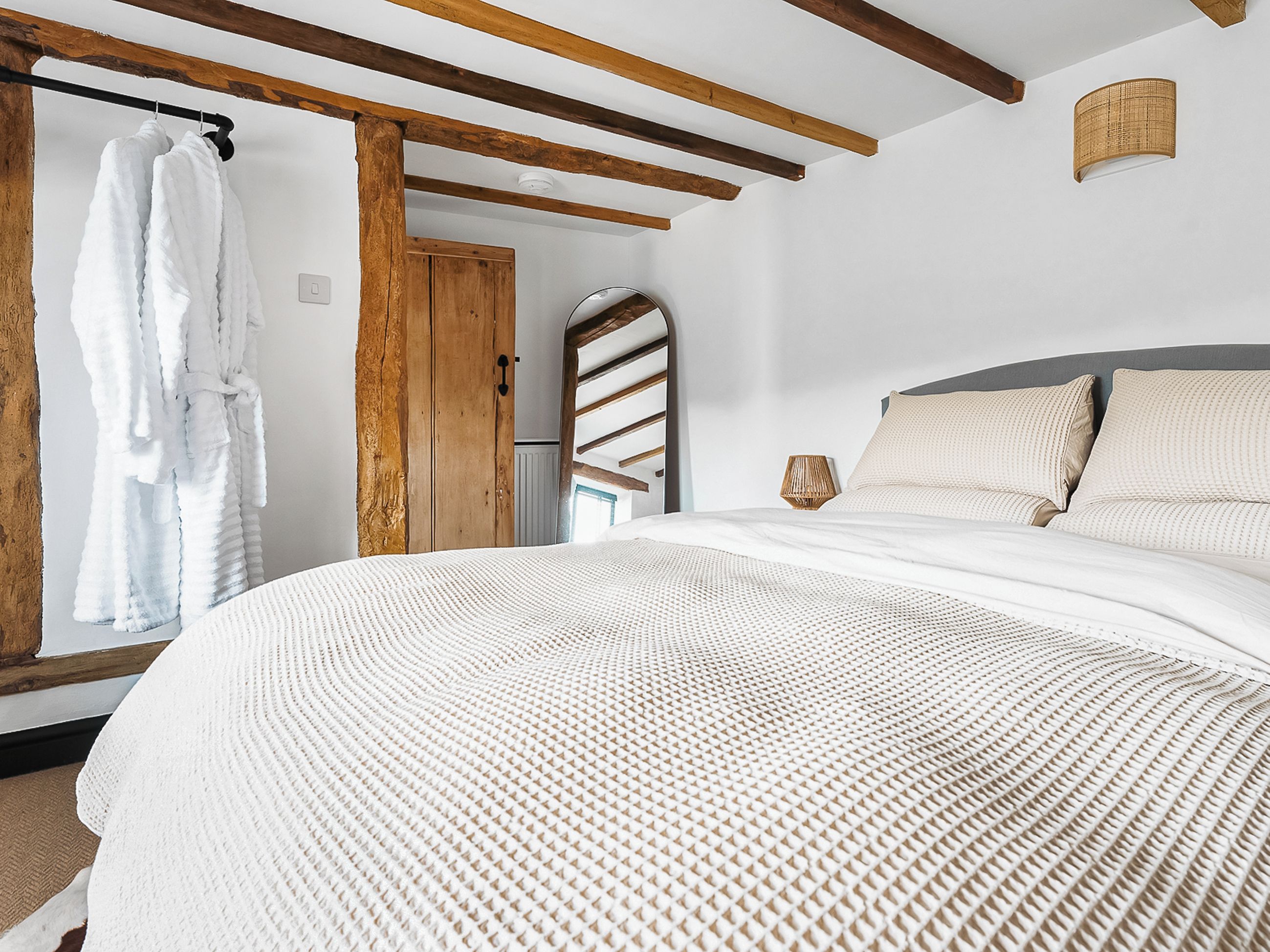 Un dormitorio con una cama grande, vigas de madera, un armario y vistas al exterior.