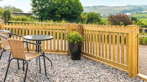 Une terrasse avec une table et des chaises, une clôture en bois et une plante en pot.