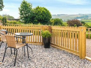 Une terrasse avec une table et des chaises, une clôture en bois et une plante en pot.