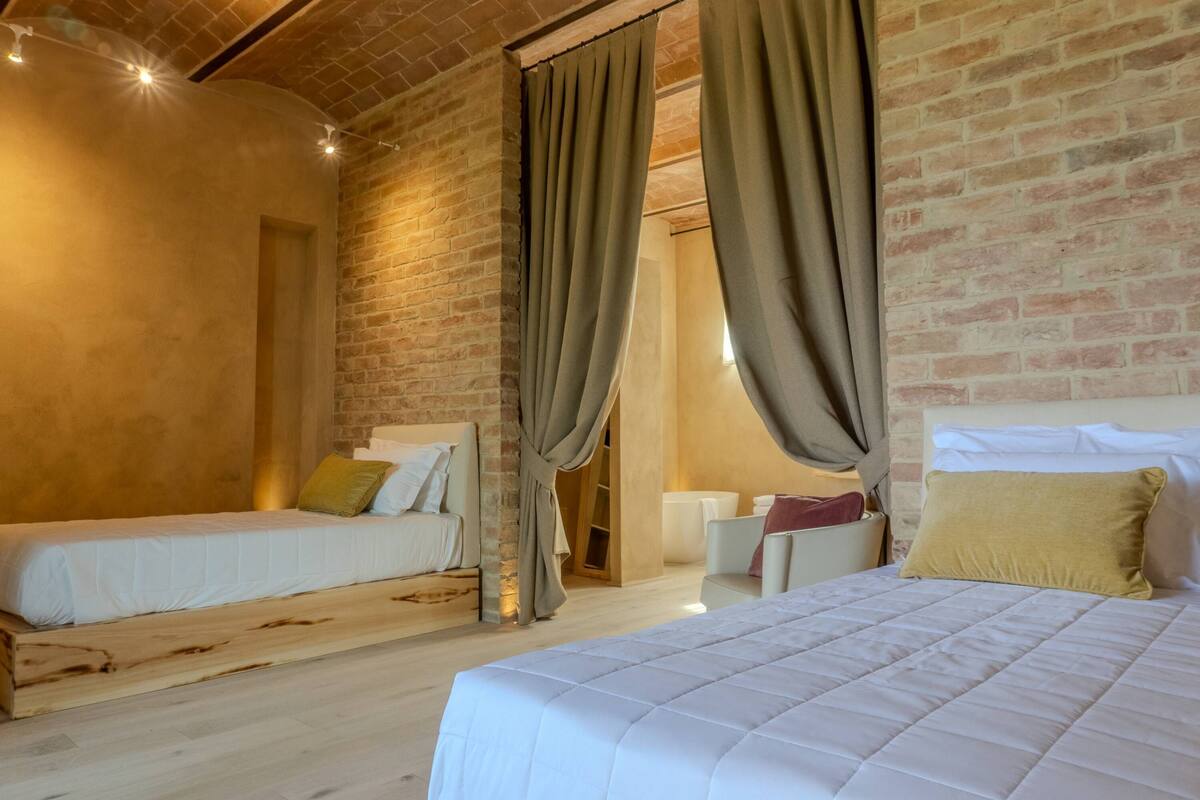 Una habitación con dos camas, una pared de ladrillo y suelo de madera.