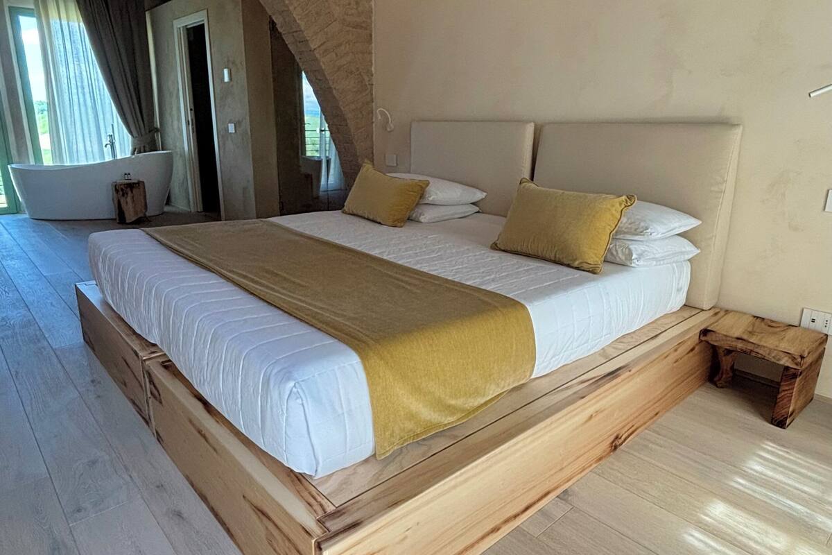 Un dormitorio espacioso con una cama grande, cabecero de madera y un banco empotrado.