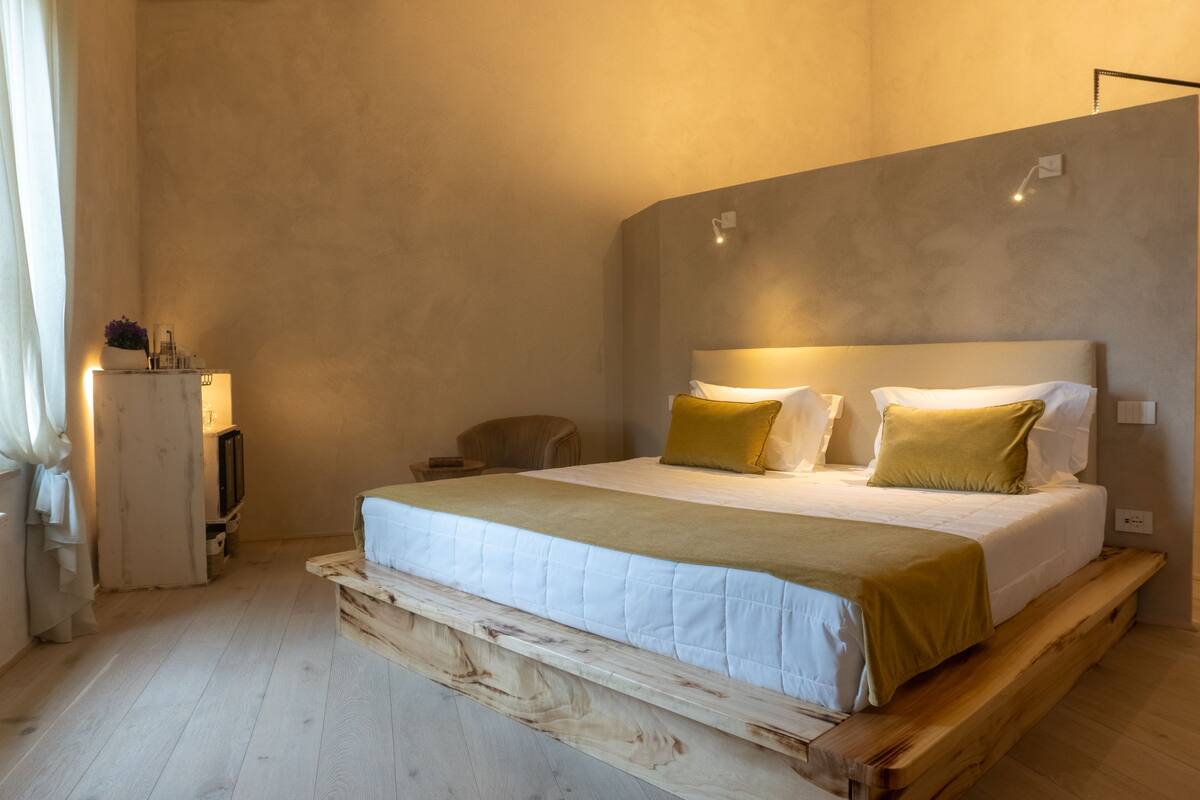 Un dormitorio con cama, mesita de noche, lámpara y un pequeño armario.