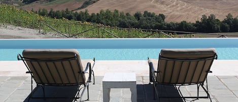 Una piscina al aire libre, sillones reclinables de piscina