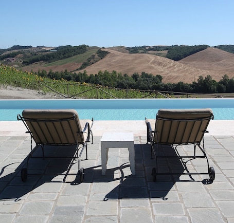 Una piscina al aire libre, sillones reclinables de piscina
