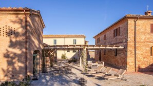 Ein Innenhof mit Sitzgelegenheiten im Freien, einer Pergola und Ziegelgebäuden.