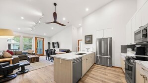 Eine moderne Küche mit Kochinsel, Edelstahlgeräten und einem Essbereich mit Sofa und Stühlen.