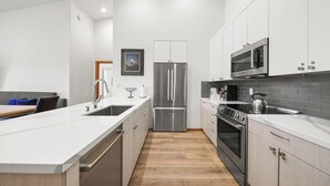 Eine moderne Küche mit Edelstahlgeräten, Holzboden und weißen Schränken.