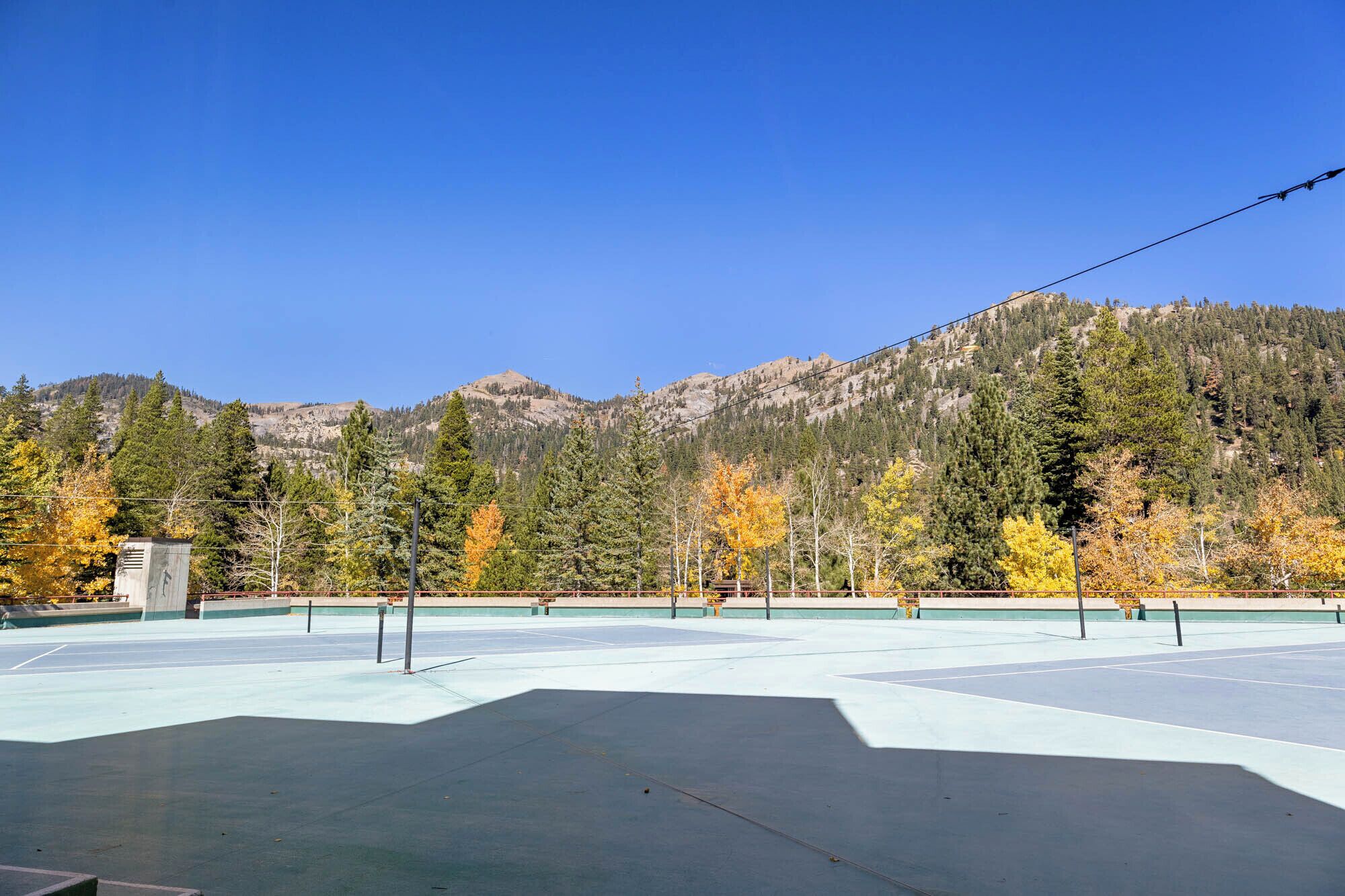 An outdoor tennis court with a mountain backdrop.