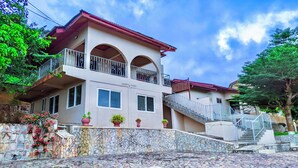A two-story house with a stone facade, a balcony, and a staircase leading to the upper level. - Charming 3-bedroom house in enchanting Aburi with WiFi, AC (Aburi)