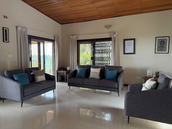 A spacious living room with two sofas, a coffee table, and a large window with curtains.