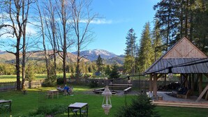 A rustic outdoor seating area with wooden tables and chairs, surrounded by a wooden fence and a view of mountains in the background. - Leśniczówka u Zięby (Koscielisko)