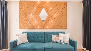 A teal sofa with patterned cushions, a wooden wall panel with lights, and dark curtains. - Sunnyside Studio w/ hot tub! (Telluride)