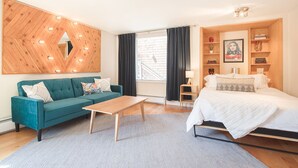 A modern bedroom with a bed, a sofa, a coffee table, and a large wooden wall decoration. - Sunnyside Studio w/ hot tub! (Telluride)