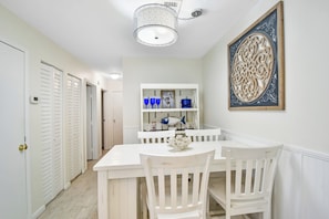 A hallway with white doors, a dining area with a white table and chairs, and a decorative wall piece. - Renovated 2br/2ba Ocean Walk. Walking distance to pier/Village area (Saint Simons Island)