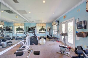 Ein Fitnessstudio mit Laufbändern, Crosstrainern, einem Ergometer und Kurzhanteln.