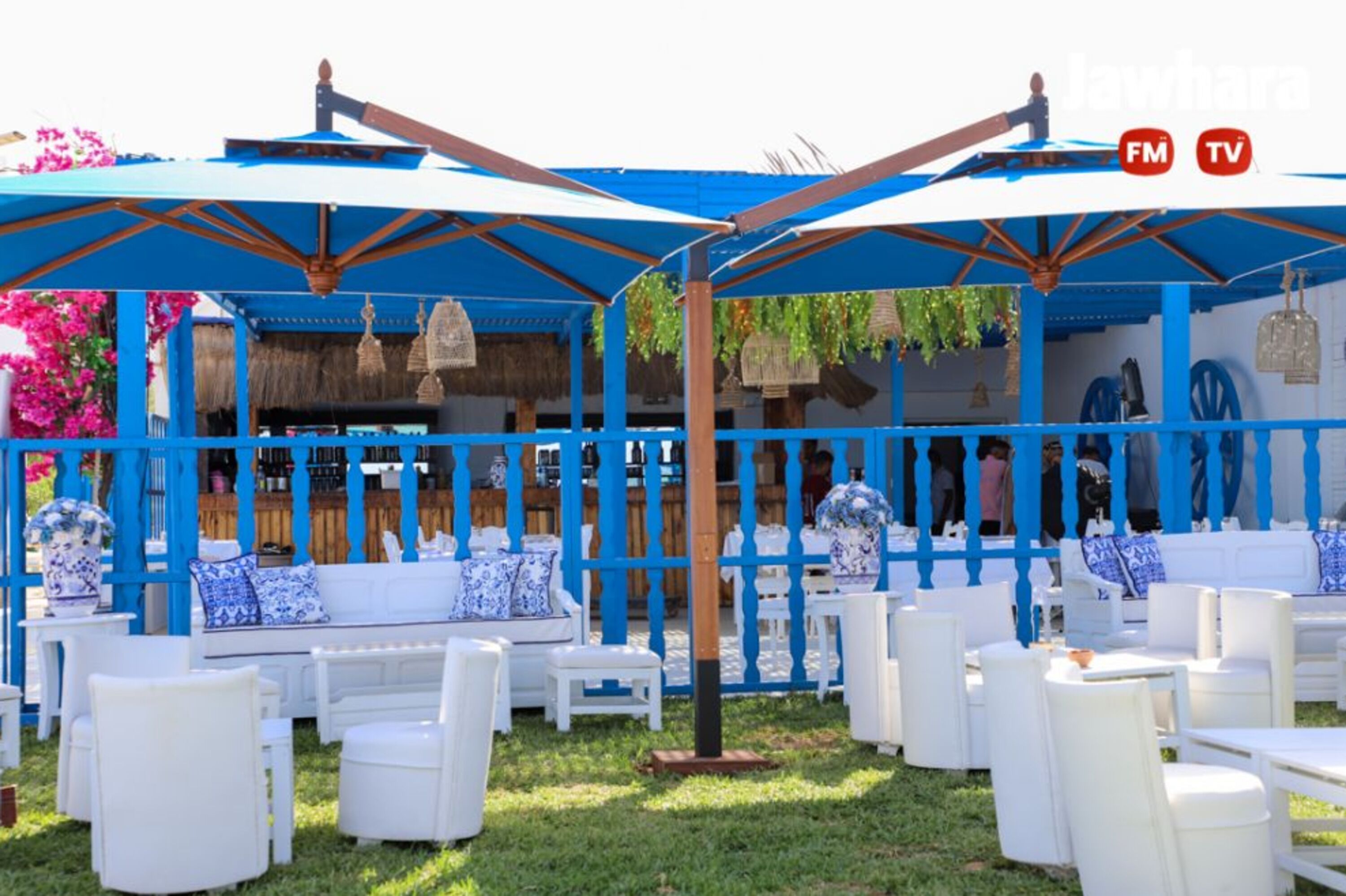 Un espace extérieur aménagé avec des meubles blancs et des parasols bleus.