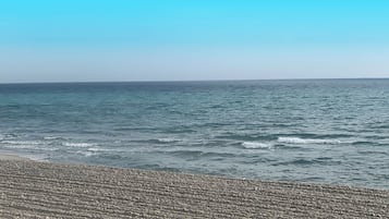 Een privéstrand, wit zand, strandlakens, een strandbar