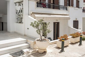 Ein weißes Gebäude mit Balkon, Stufen und Topfpflanzen.