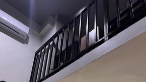 A modern kitchen with a black railing, a flat-screen TV, and a coffee cup on the counter.