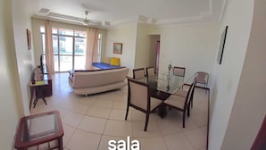 A room with a bed, a glass dining table, and a TV. - Apto. Amplo, à 200 mts da Bela Praia do Forte e 2 Vagas de Garagem (Algodoal Cabo Frio)