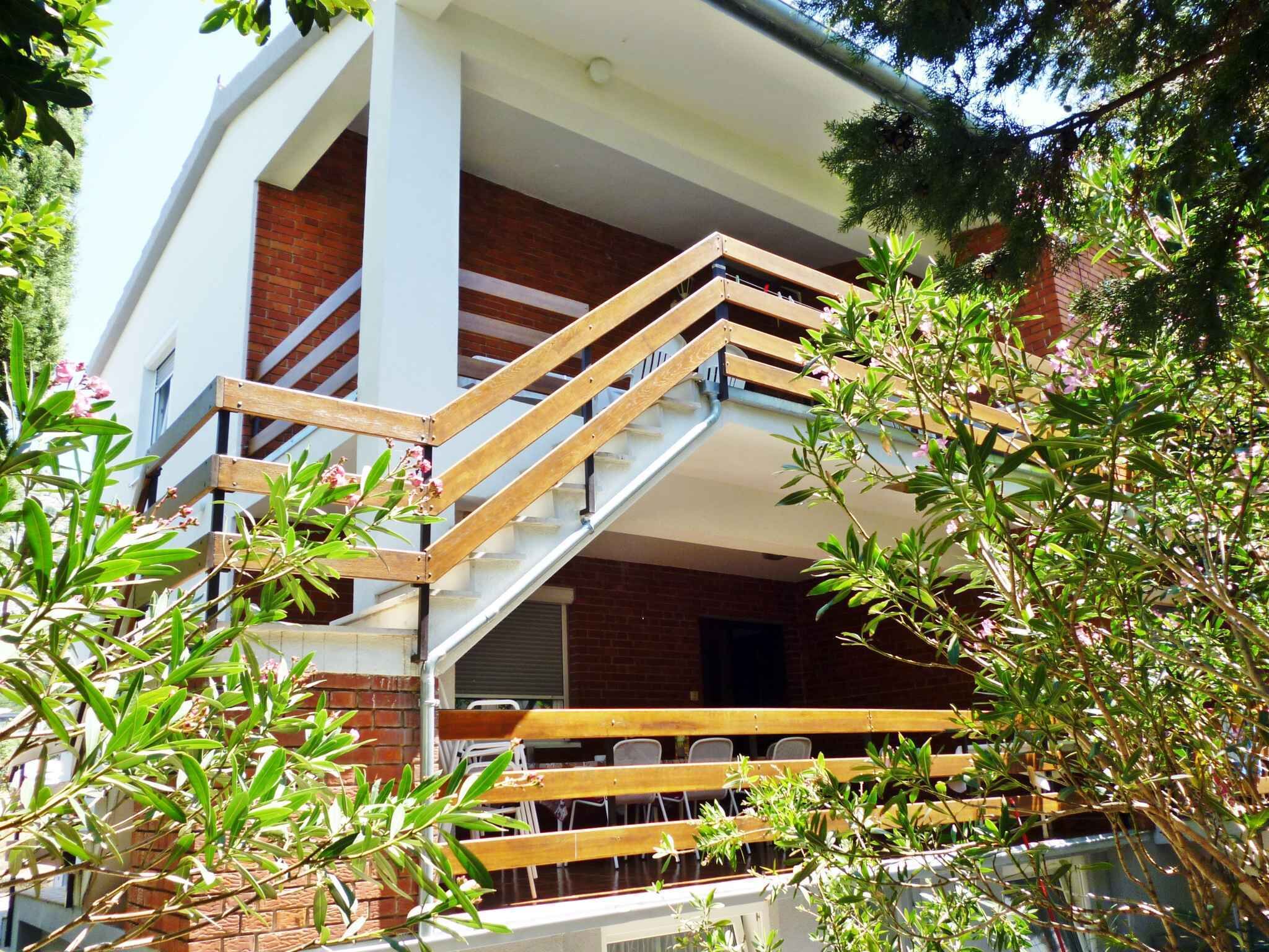 A multi-level building with a staircase, outdoor seating, and surrounding greenery.