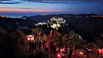A mountain village at night with illuminated buildings and a view of the surrounding landscape.