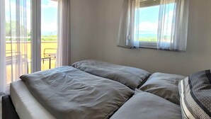 Et værelse med to senge, en balkon og et vindue med gardiner.