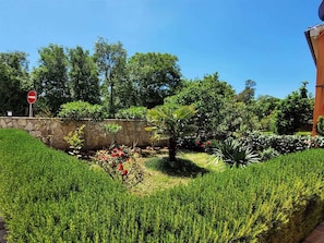 Jardim com muro de pedra, diversas plantas e placa de proibido a entrada.