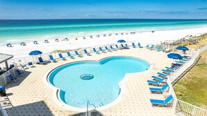 A pool area with lounge chairs and umbrellas, a white sandy beach, and a clear blue ocean. - Beach House 104A - Gulf Front Resort! (Miramar Beach)