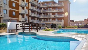Un immeuble résidentiel à plusieurs étages doté de balcons, d’une piscine et d’espaces de détente en plein air.
