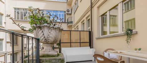 A balcony with a white sofa, a table with two glasses, and a potted plant.