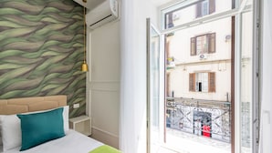 Habitación de hotel con cama, pared de diseño verde y balcón con vista a la calle.