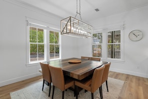 Un comedor con una mesa de madera, seis sillas y una lámpara colgante.