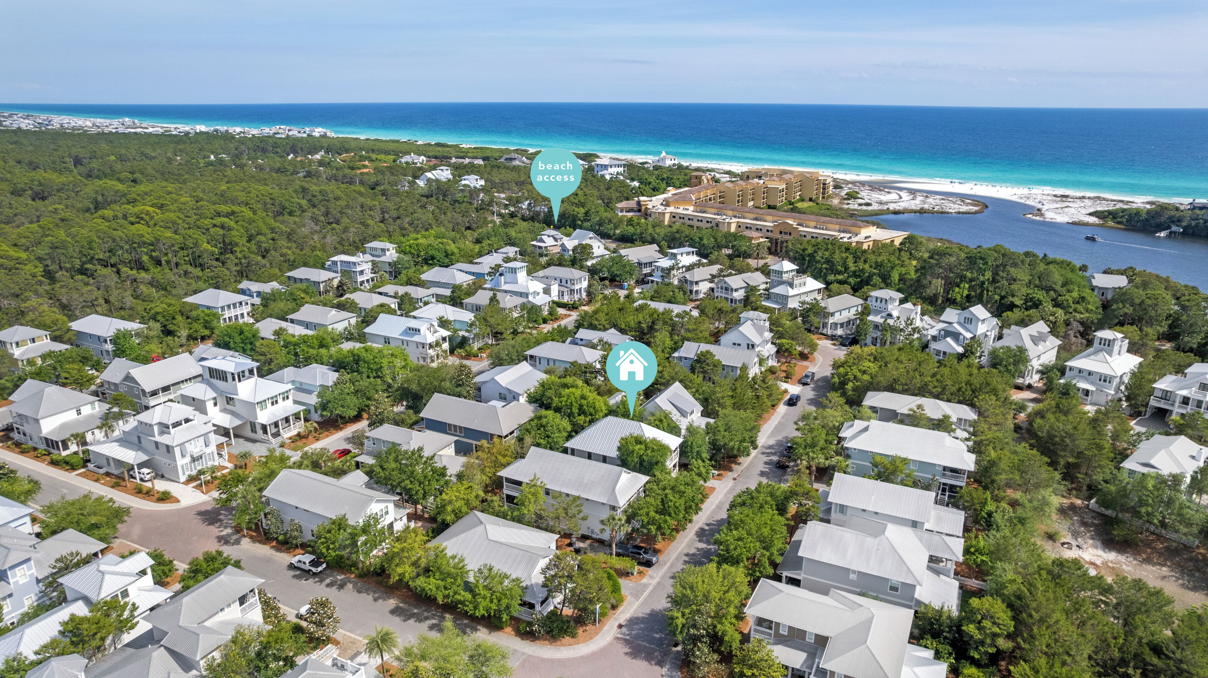 Una vista aerea di una zona residenziale con case, una spiaggia e una visuale chiara sull'oceano.