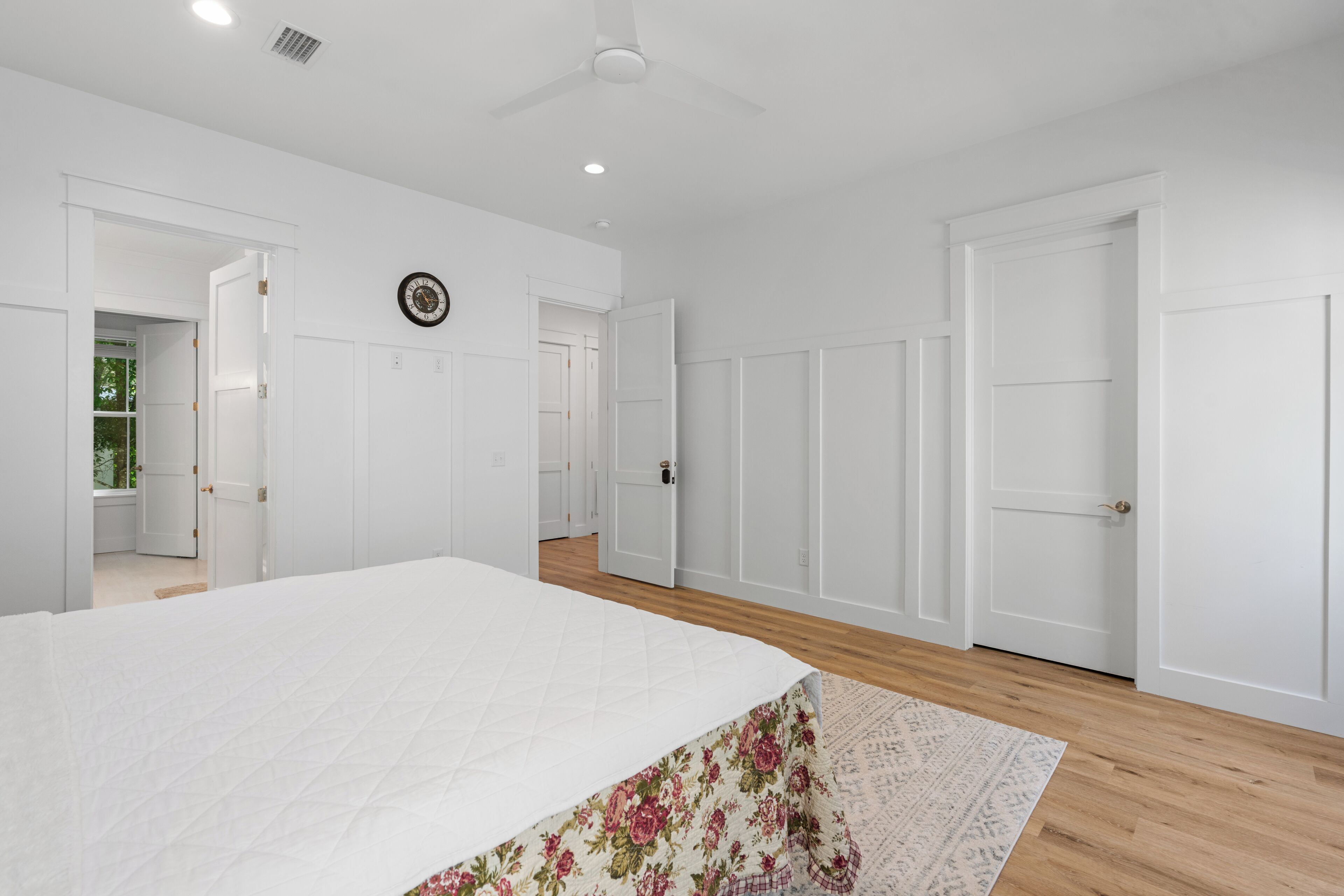 A bedroom with a bed, a ceiling fan, and white doors.