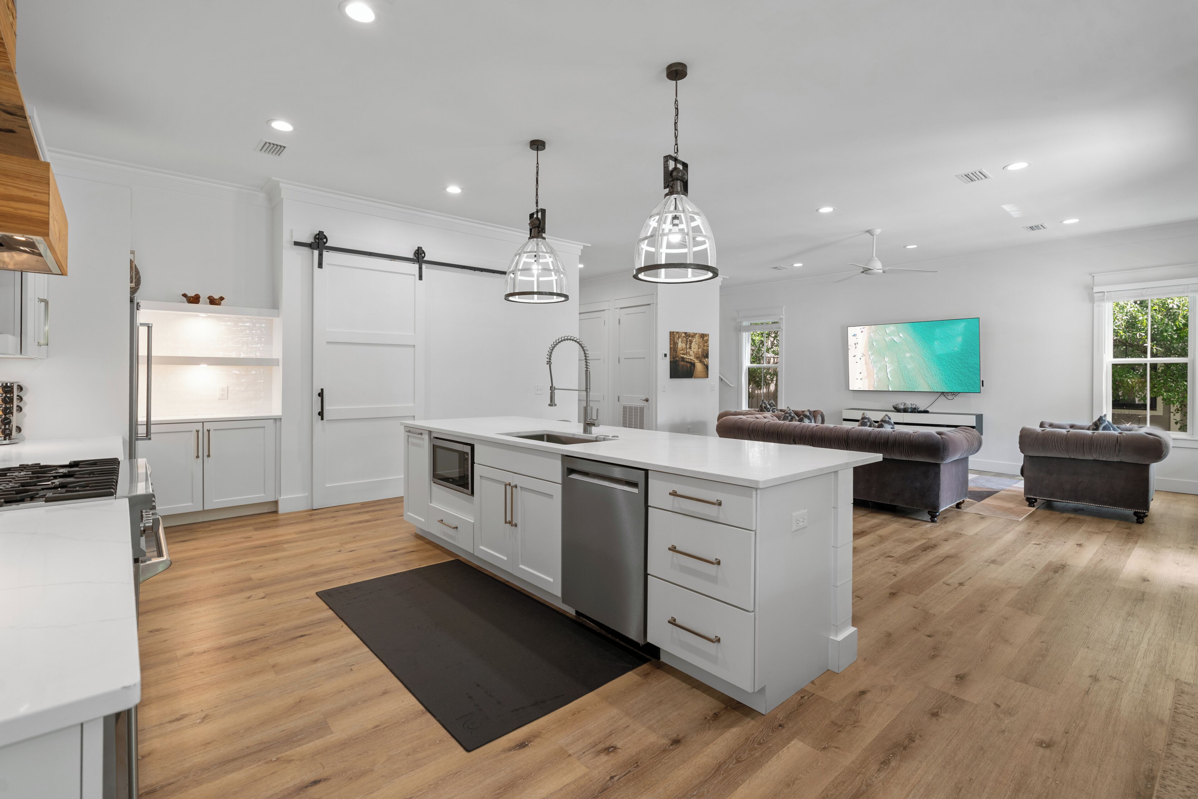 Una cocina moderna con armarios blancos, una isla central e iluminación colgante.