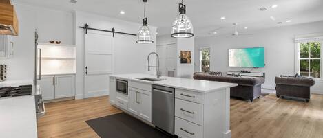 A modern kitchen with white cabinetry, a central island, and pendant lighting.