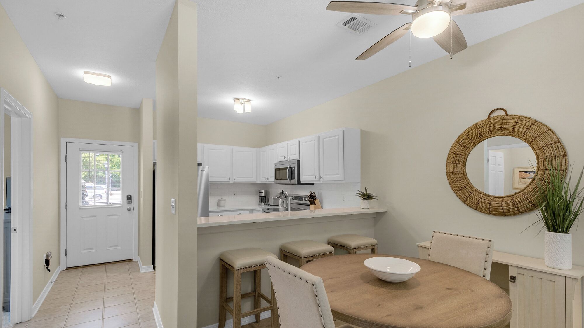 A modern kitchen with white cabinets, a microwave, and a ceiling fan.