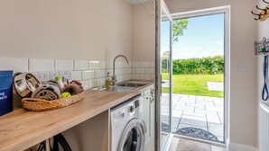 Une cuisine moderne équipée d’un lave-linge, d’un évier et d’un panier rempli de friandises pour chiens.