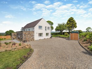 A two-story house with a stone facade and a gravel driveway leading to a wooden gate. - Llwyncelyn Farmhouse (Clynderwen)