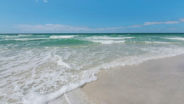 A beach with waves approaching the shore under a clear sky. - 1st Floor Gulf Side- Lagoon Pool- Beach Chair Setup (Panama City Beach)